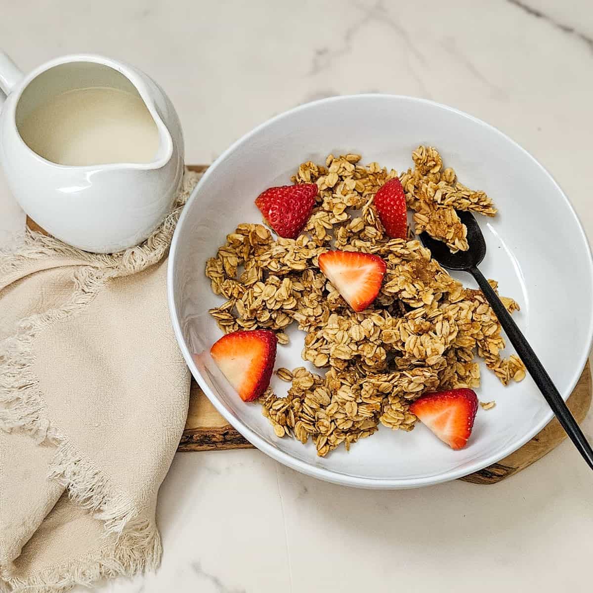 Crunchy homemade granola with fresh strawberries in a white bowl.