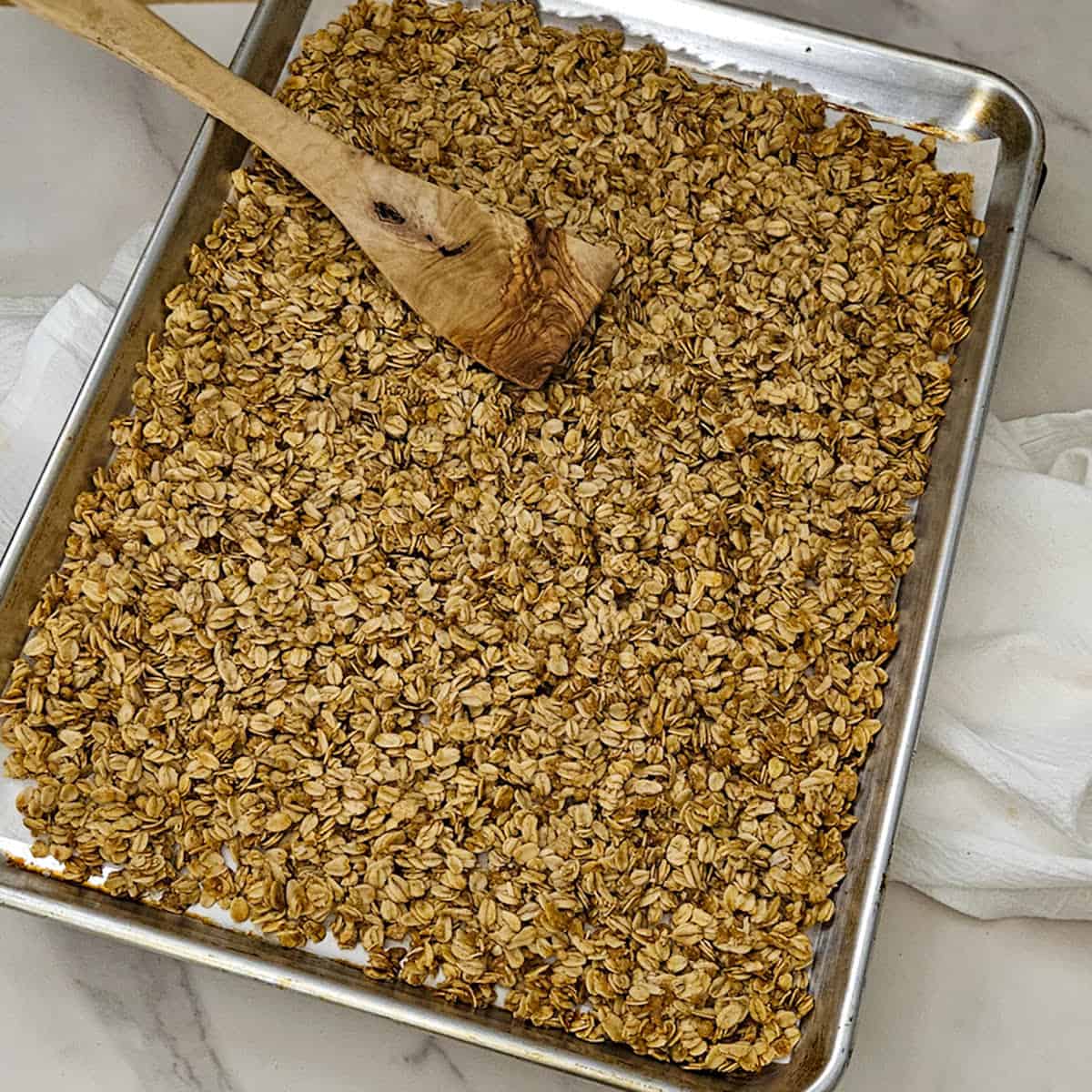 Crunchy homemade granola clusters on baking sheet.