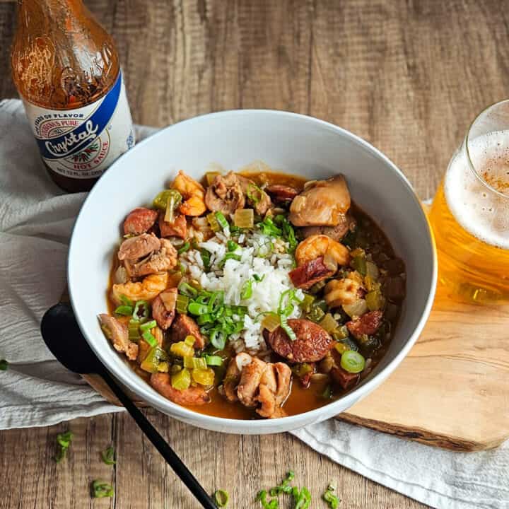Delicious gumbo and rice, served with a cold beer on a wooden table.