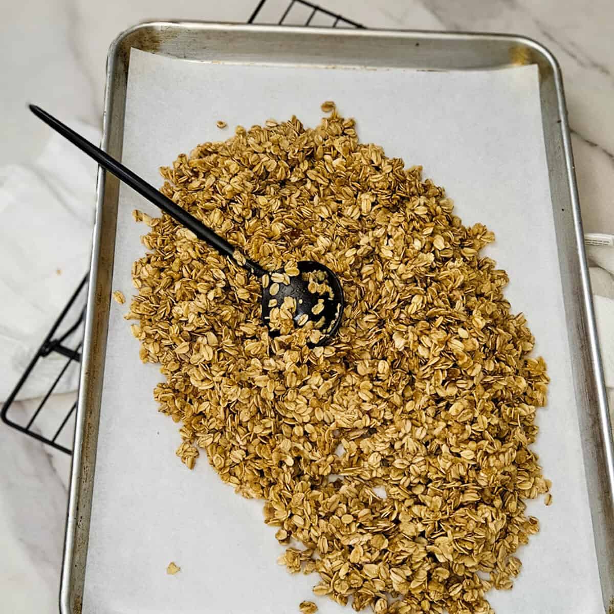 Spreading the chai spice granola mixture onto a baking sheet pan.