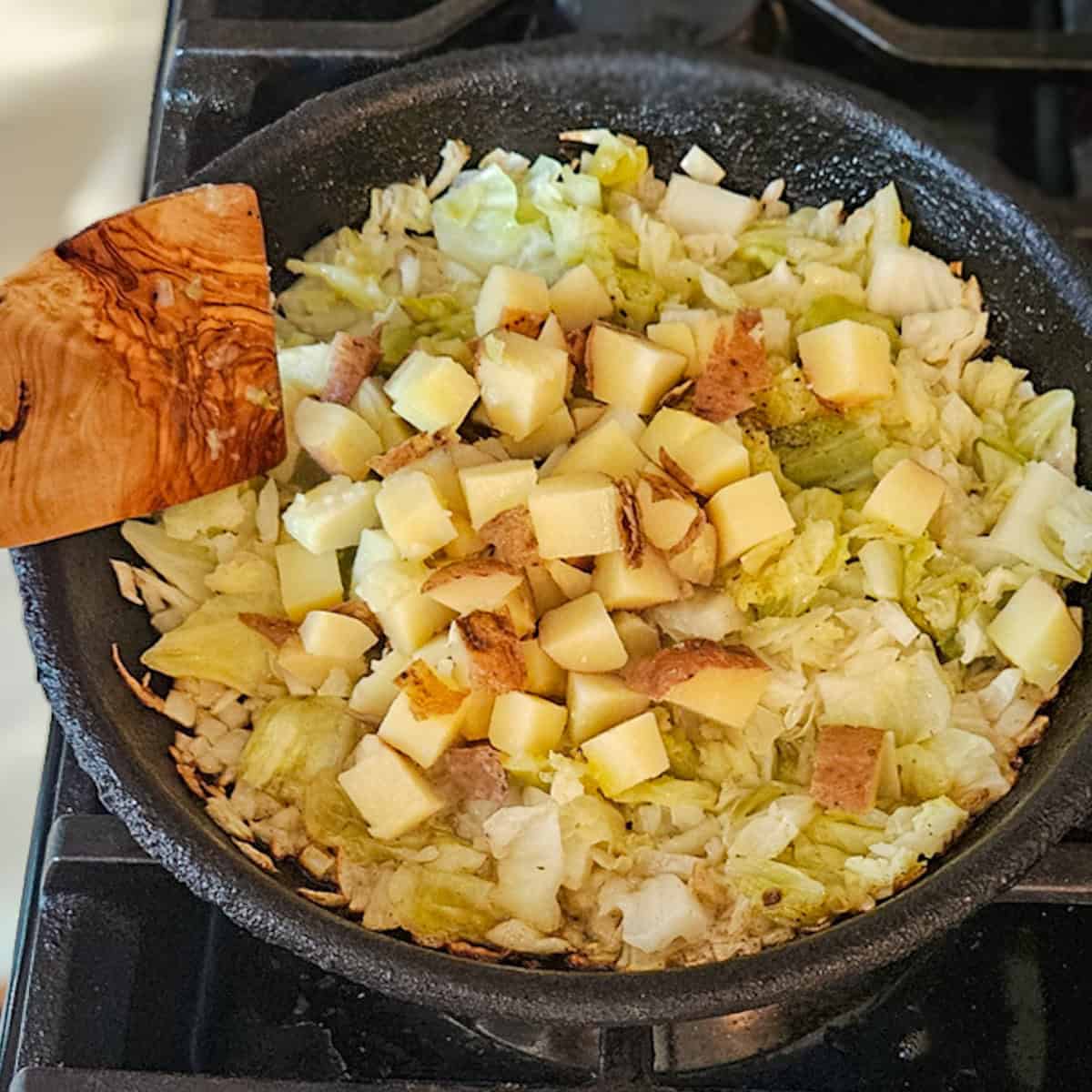 Adding potatoes to a skillet for corned beef and cabbage hash.