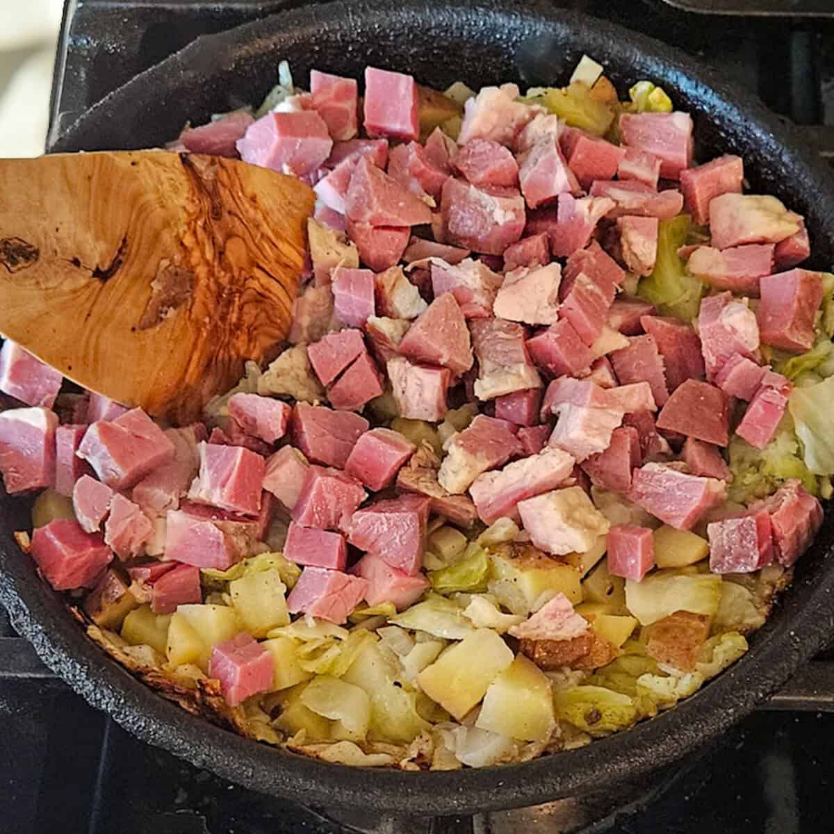 Adding corned beef to the skillet for the corned beef and cabbage hash.