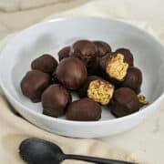 Delicious chocolate peanut butter protein balls in a white bowl.