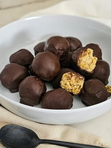 Delicious chocolate peanut butter protein balls in a white bowl.