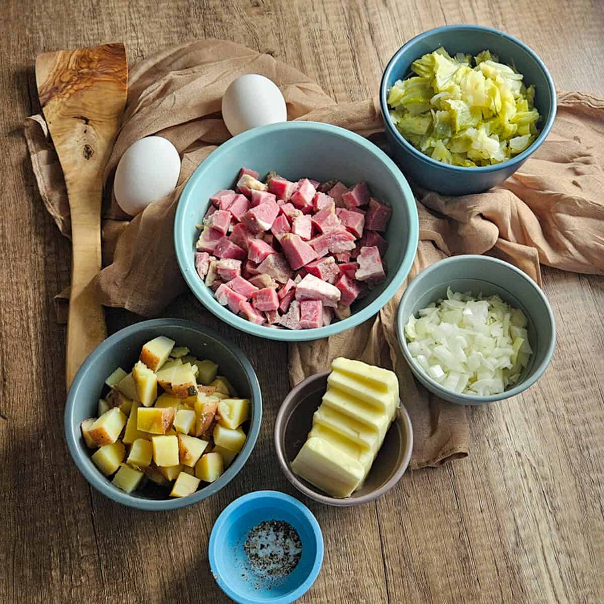 The ingredients for corned beef and cabbage hash measured out with eggs and a spatula.