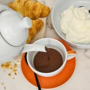 French hot chocolate with croissants and cream on a marble table.