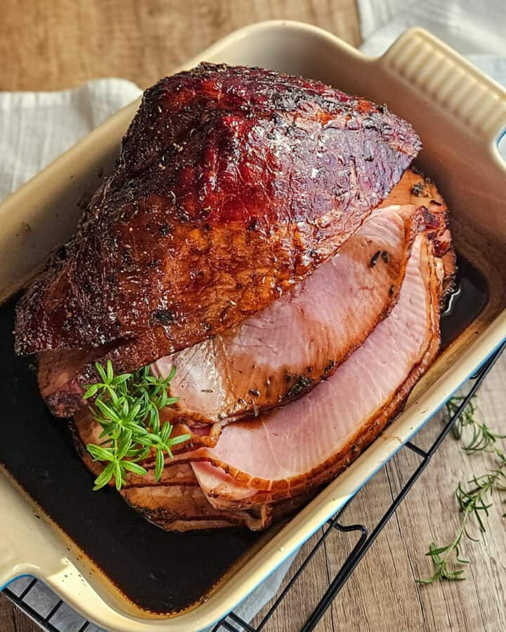 glazed ham with herbs and juices, perfect for holiday dinners.