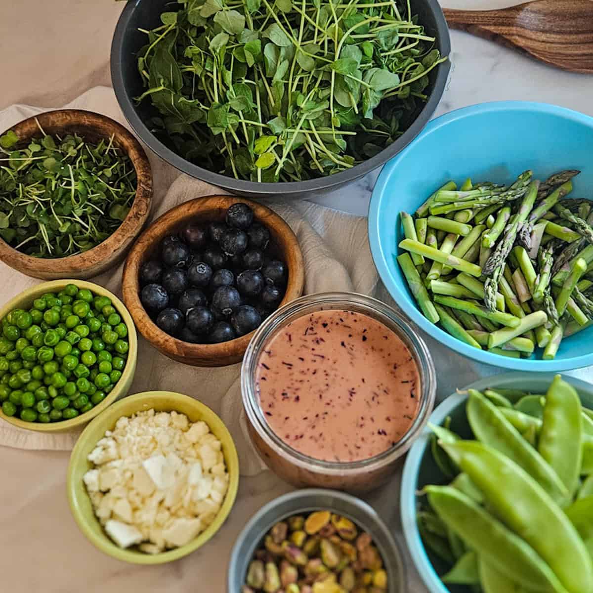 All of the ingredients for the pea and asparagus salad measured out into separate bowls.