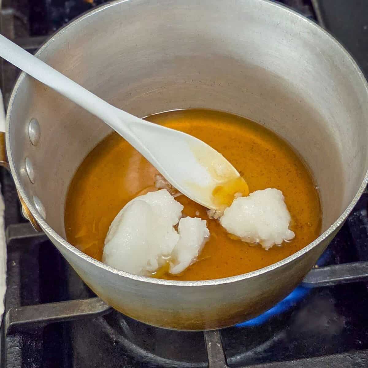 Melting coconut oil , honey, and vanilla together in a pot on the stove with a spoon.